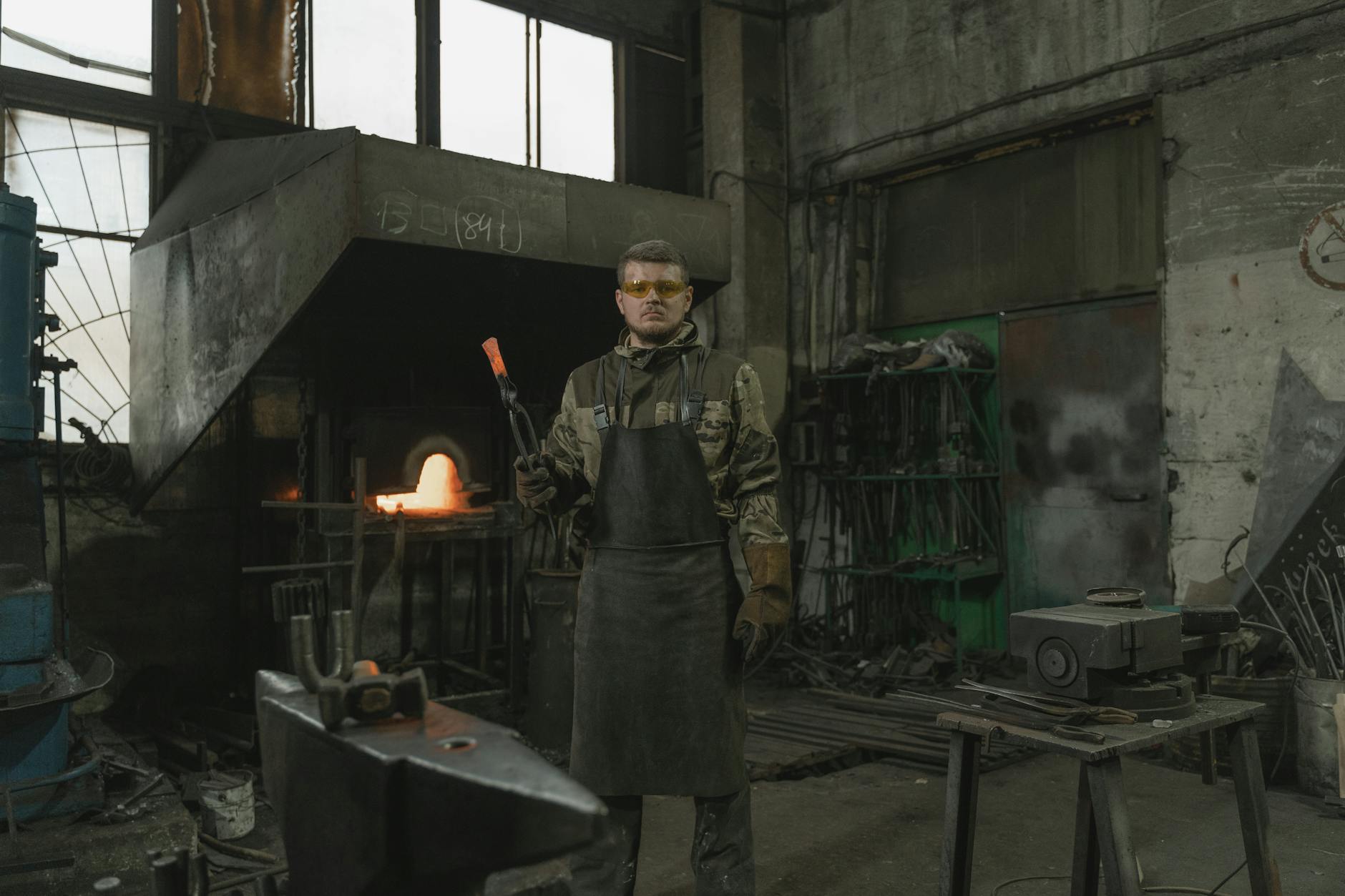 Caucasian blacksmith working at forge, showcasing industrial craftsmanship.