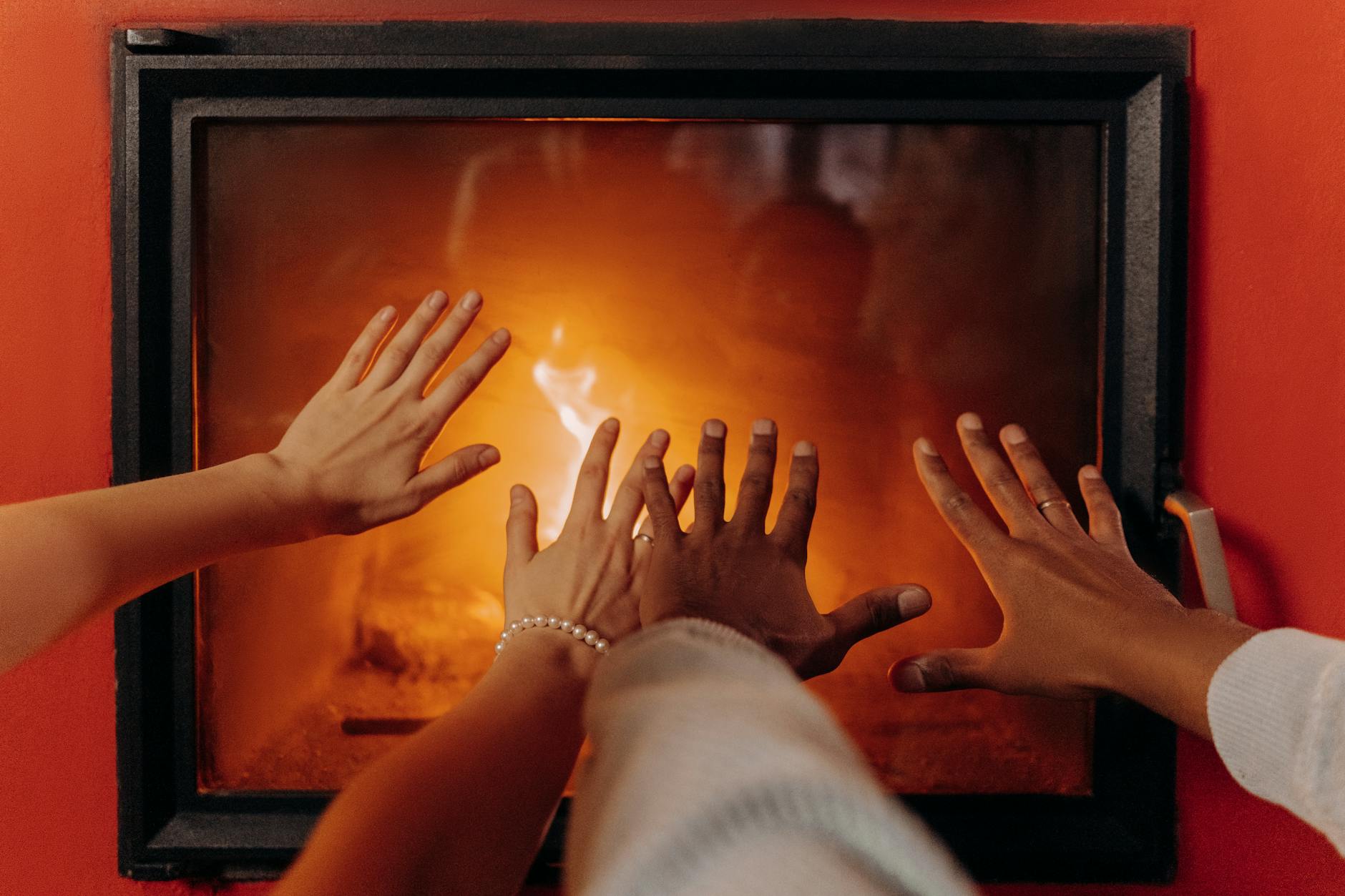 Close-up of hands warming by a cozy fireplace, radiating warmth and comfort.